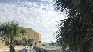 A wooden boardwalk leading to a building with a flat roof and multiple windows.
