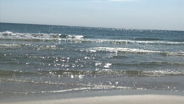 A beach with waves and a clear sky.