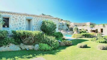 A stone building with a pool and lush garden.