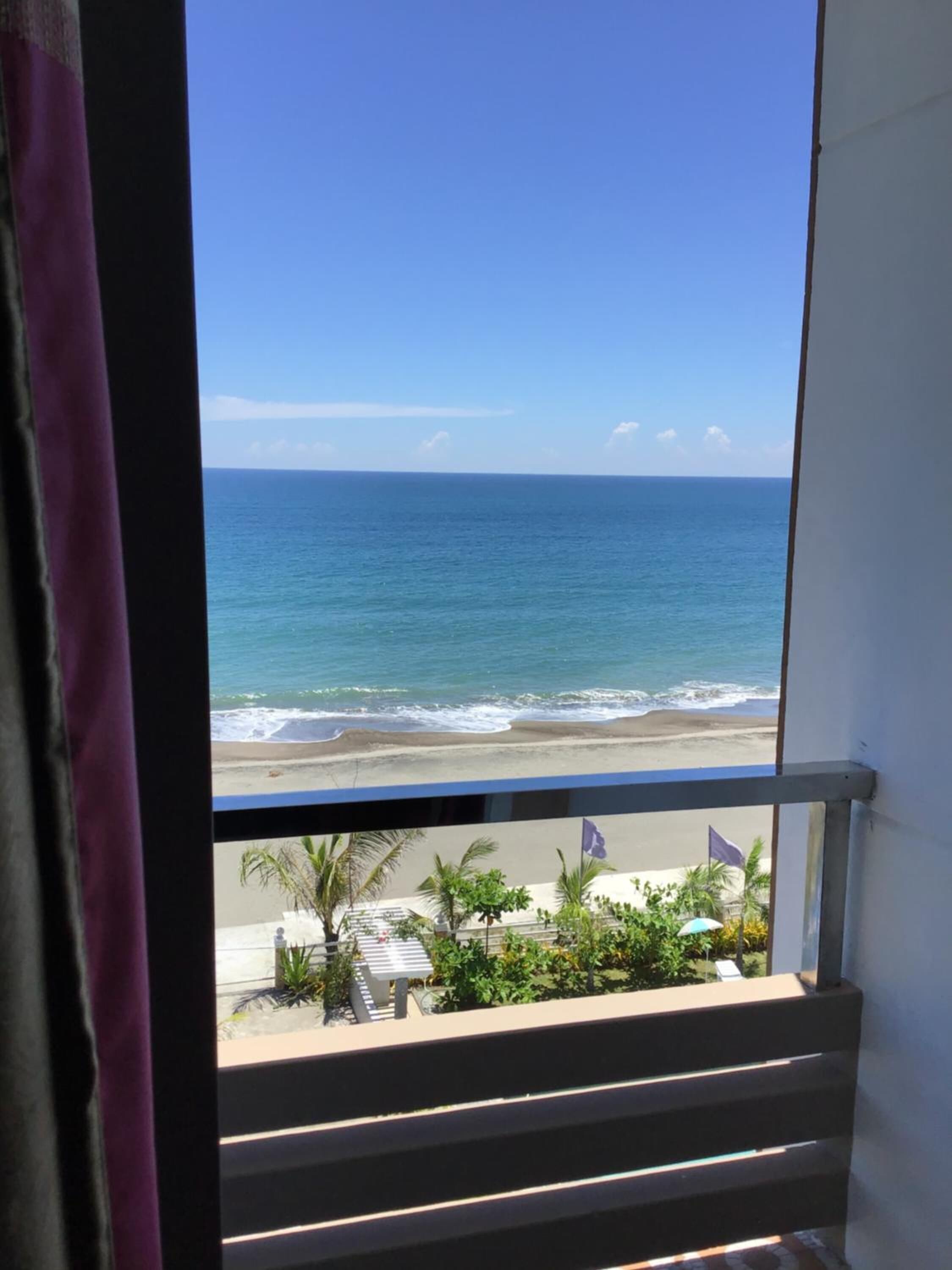 Ein Balkon mit Blick auf den Ozean und den Strand.
