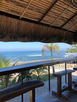 A beachside patio with wooden benches and a thatched roof. - EM Royalle Hotel & Beach Resort (San Juan)