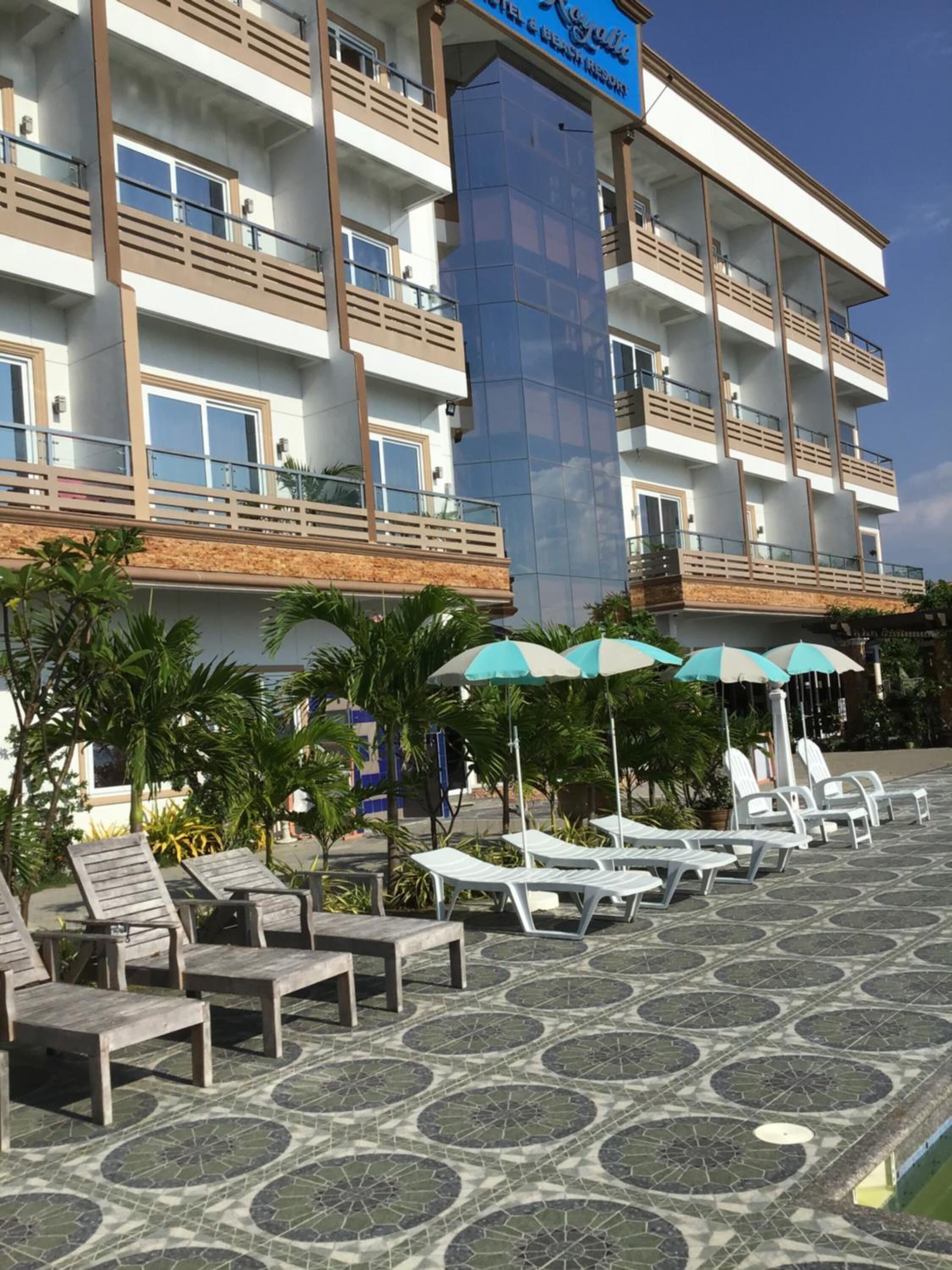Un hotel con varios balcones, mobiliario exterior y una zona de piscina.