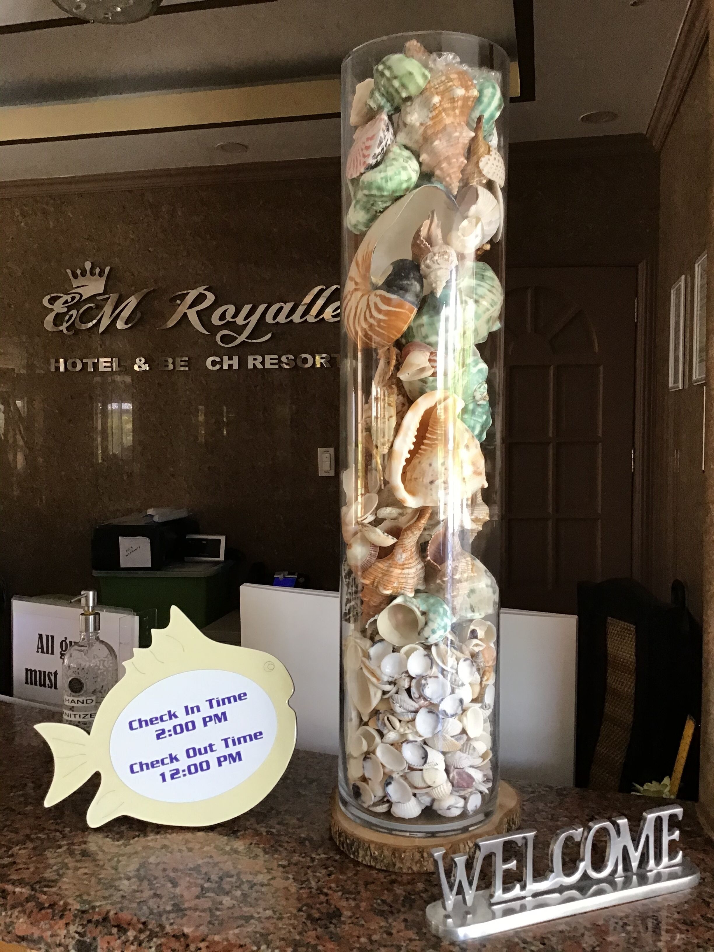 A glass display with various seashells and a welcome sign.