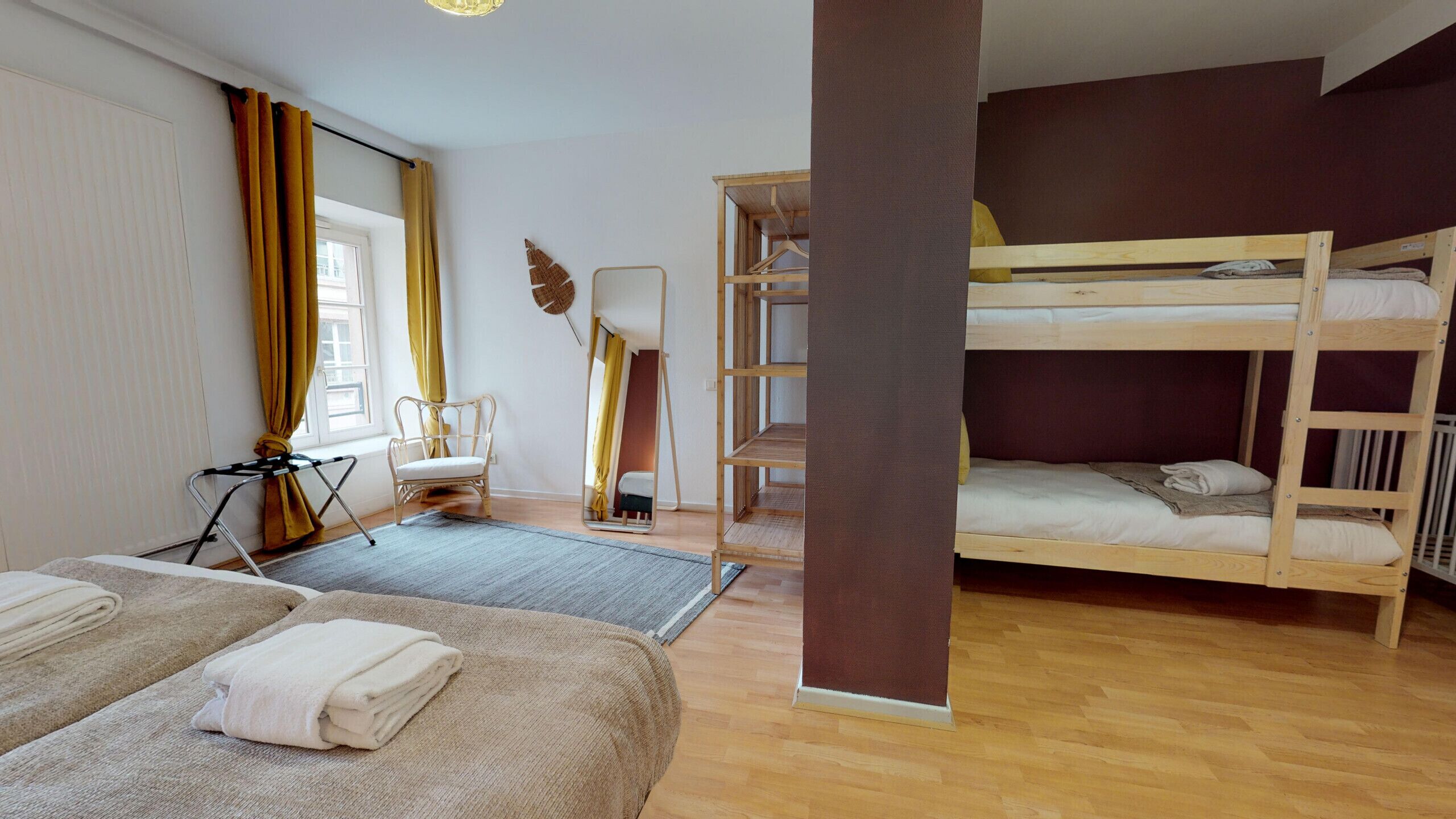 A room with two beds, a chair, a mirror, and a wooden bunk bed.