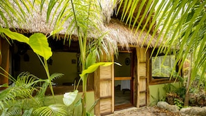 A thatched-roof hut with a stone pathway leading to a wooden door. - Aldea JOYAH (Tulum)