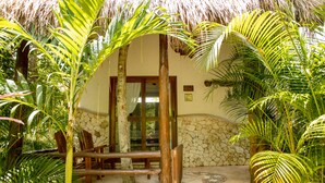 A tropical resort entrance with a stone wall, wooden bench, and palm trees. - Aldea JOYAH (Tulum)