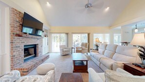 A spacious living room with a brick fireplace, comfortable seating, and large windows. - Very Nice Home Located on the 11-Mile Lagoon with Its Own Large Private Pool! (Hilton Head)