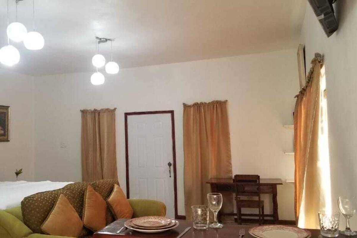 A hotel room with a bed, a dining table with chairs, and a small table with glasses.