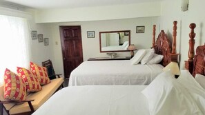 A hotel room with two beds, a wooden headboard, a desk with a lamp, and a large mirror. - Wilton House (Bluefields)