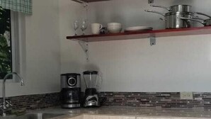 Una cocina con isla en esquina, armarios de madera, cafetera y lámparas colgantes.
