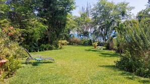 Un jardín bien cuidado con césped, una silla de metal y una pequeña mesa.