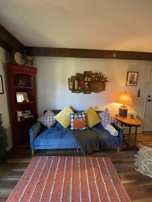 A cozy living room with a blue sofa, patterned cushions, a red bookshelf, and a wooden wall decor. - Sugar Ski Premium Efficiency (no loft) - Unit 11-402 (Sugar Mountain)