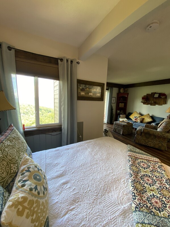 A bedroom with a large bed, a window with curtains, a sofa, and a small table. - Sugar Ski Premium Efficiency (no loft) - Unit 11-402 (Sugar Mountain)