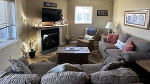 Una sala de estar con sofá, sillón y televisor.