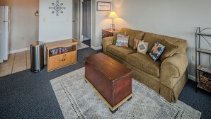 A living room with a brown sofa, a wooden chest, a metal trash bin, a lamp, and a patterned rug. - Sugar Ski Economy Efficiency (no loft) - Unit 11-601 (Sugar Mountain)