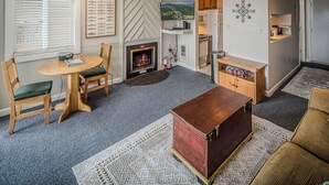 A cozy living room with a fireplace, a dining table, and a TV mounted on the wall. - Sugar Ski Economy Efficiency (no loft) - Unit 11-601 (Sugar Mountain)