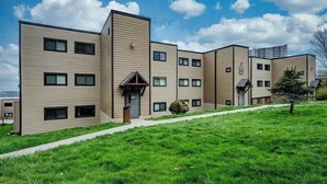 A modern multi-story residential building with a flat roof, large windows, and a well-maintained lawn. - Sugar Ski Comfort Two Bedroom - Unit 313 (Sugar Mountain)