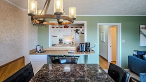 A dining area with a marble table, black leather chairs, and a chandelier. - Sugar Ski Comfort Two Bedroom - Unit 313 (Sugar Mountain)