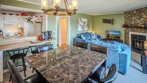 A modern kitchen with a marble island, a dining area with a large table, and a cozy living room with a fireplace. - Sugar Ski Comfort Two Bedroom - Unit 313 (Sugar Mountain)