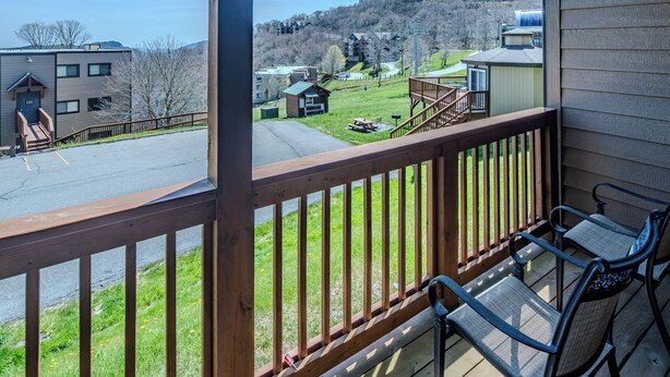 A balcony with a view of a parking lot, a grassy area, and buildings in the background. - Sugar Ski Comfort Two Bedroom - Unit 313 (Sugar Mountain)