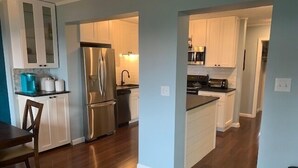Una cocina moderna con electrodomésticos de acero inoxidable, armarios blancos y una mesa de comedor de madera.