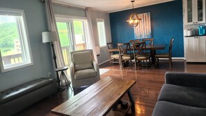 Un comedor con una mesa y sillas de madera, un banco y vistas al exterior con vegetación.