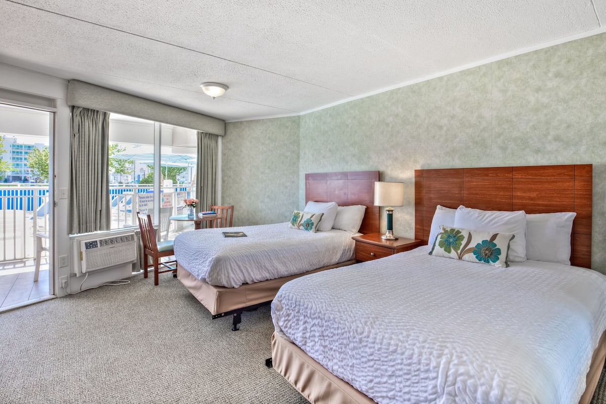 Een hotelkamer met twee bedden, uitzicht op de omgeving en een klein tafeltje met een stoel.