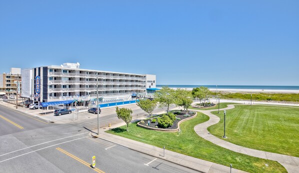 A multi-story hotel with a blue and white facade, located near a beach with a clear sky. - Armada By-the-Sea (Wildwood Crest)