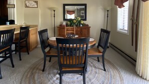 Un coin repas comprenant une table ronde, quatre chaises, un vase central et un miroir placé au-dessus de la table.