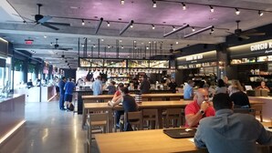 A modern restaurant with a bar area, wooden tables, and a ceiling with exposed beams and lighting fixtures. - SPACIOUS SOBE CORNER ONE BEDROOM---EXCELLENT LOCATION (Miami Beach)