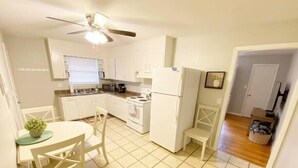 A compact kitchen with white cabinets, a stove, a microwave, and a refrigerator. There is a dining table with chairs and a ceiling fan. - St. Elmo Abode-3 mi to Ruby Falls (Chattanooga)