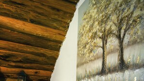 A cozy room with a wooden ceiling, a painting of a tree, and a plush sofa with checkered pillows.