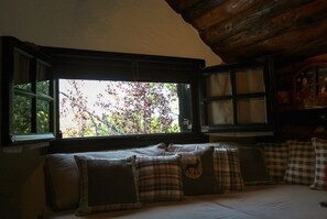 Une pièce chaleureuse avec une grande fenêtre, un plafond en bois et un lit agrémenté de plusieurs oreillers.