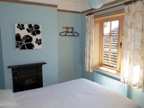 Ein Schlafzimmer mit Bett, Wandgarderobe, Heizkörper und einem Fenster mit Vorhängen.