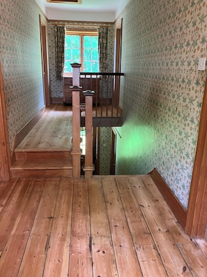 A wooden staircase leading to a balcony with floral wallpaper and a window with curtains. - Large Arts & Crafts Cottage with 7 bedrooms in Lymington near the coast (Lymington)