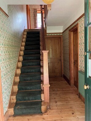 Una escalera de madera con barandilla alfombrada que lleva a una puerta.