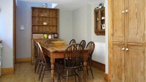 A dining area with a wooden table and chairs, a kitchen with wooden cabinets, and a large wooden wardrobe. - Large Arts & Crafts Cottage with 7 bedrooms  in Lymington near the coast (Lymington)