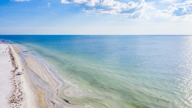 Une plage à l’eau turquoise et limpide, bordée d’un rivage sablonneux.