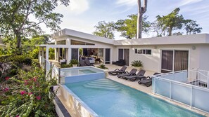 Una casa moderna amb piscina, mobiliari exterior i jardí.
