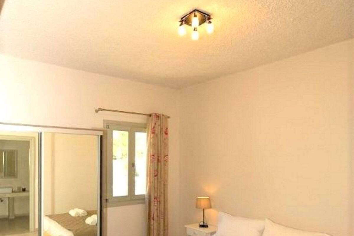 A bedroom with a bed, a bedside table, a lamp, and a mirror.
