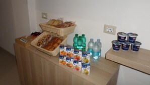 Un buffet proposant du pain, des viennoiseries et diverses boissons, notamment de l’eau et du jus de fruits.