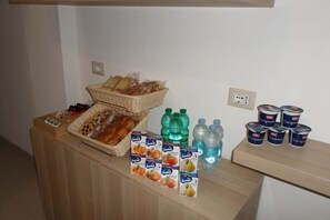 A buffet setup with bread, pastries, and various beverages including water and juice. - B&B Mansarda del Sole (Naples)