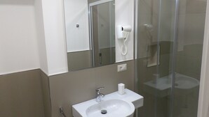 Une salle de bain avec un lavabo blanc, un miroir et une douche à parois de verre.