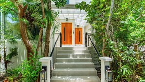A staircase with wooden doors at the top, surrounded by lush greenery. - Stunning 1BR Ocean Vw + Jacuzzi SUV Kite Boarding - Wyakha 4 Ocean View (Long Bay)