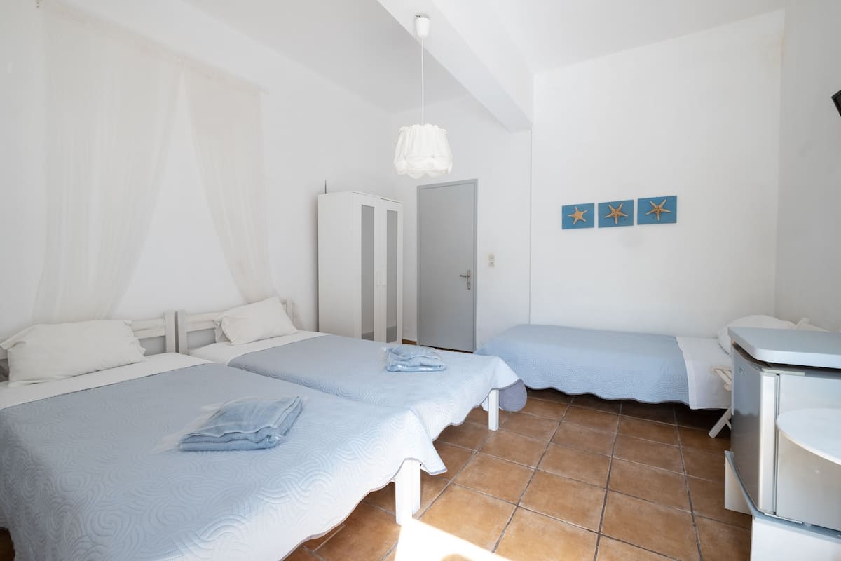 A room with two beds, a wardrobe, a desk, and a wall with starfish decorations.