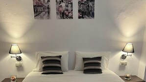 Cama doble con cubrecama acolchado, dos mesitas de noche con lámparas y dos toallas sobre la cama.