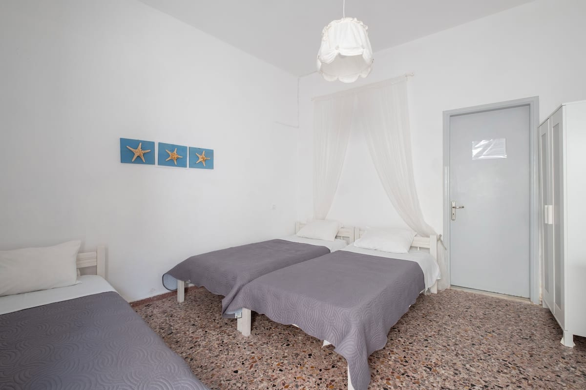 A bedroom with two beds, a white door, and a wall with starfish decorations.