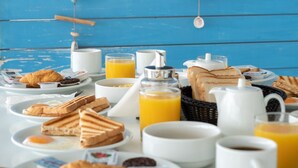 Una mesa de desayuno con diversos alimentos y una pared de madera azul al fondo.