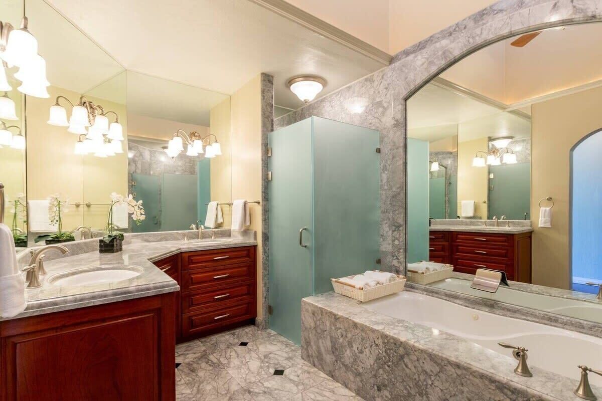 A modern bathroom with two sinks, a large mirror, and a shower area.
