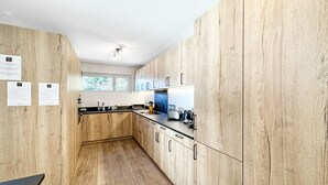 Une cuisine moderne avec des meubles en bois, un plan de travail noir et une fenêtre qui laisse entrer la lumière naturelle.